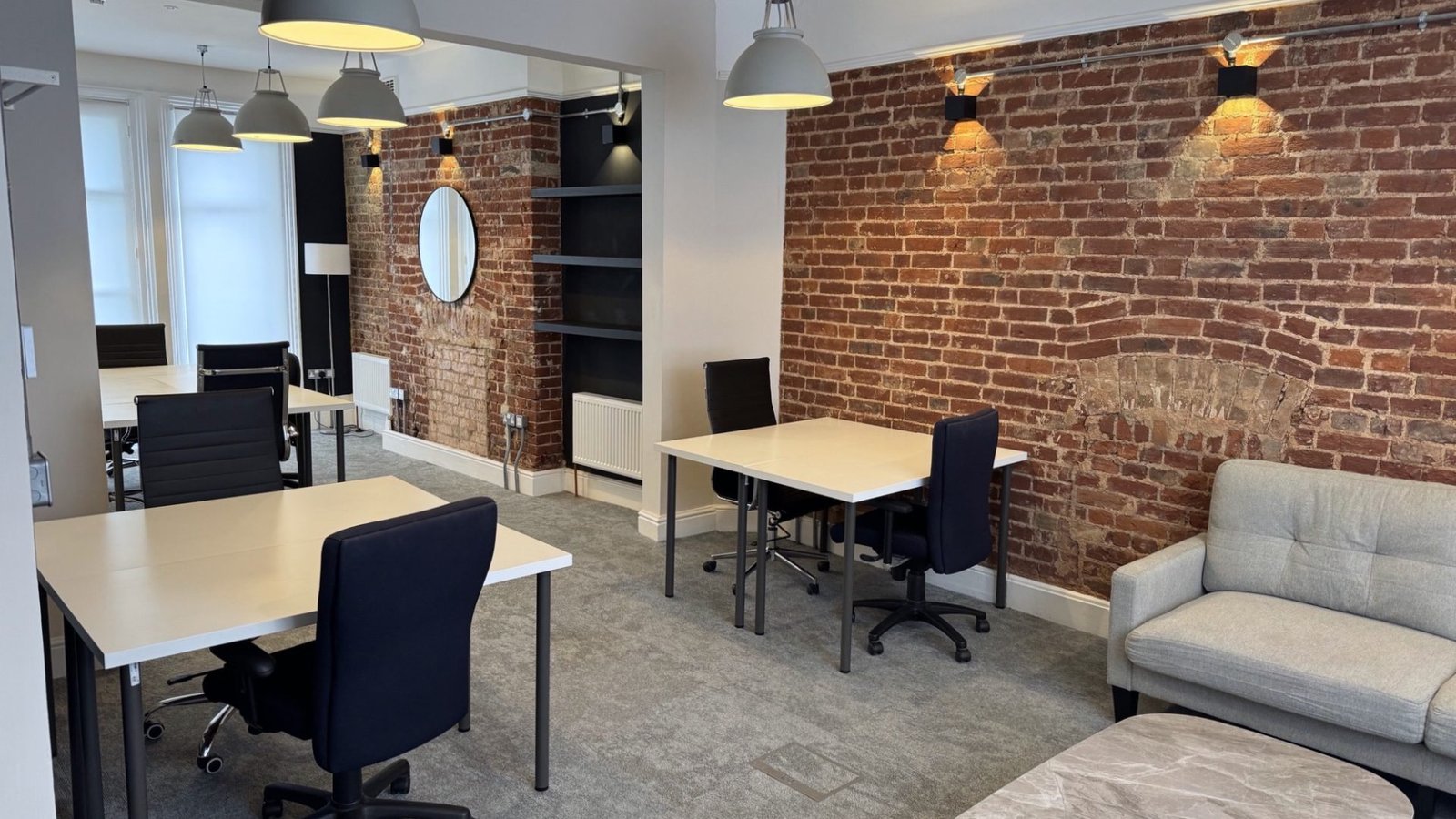 Modern renovated office space with exposed brick wall and pendant lighting