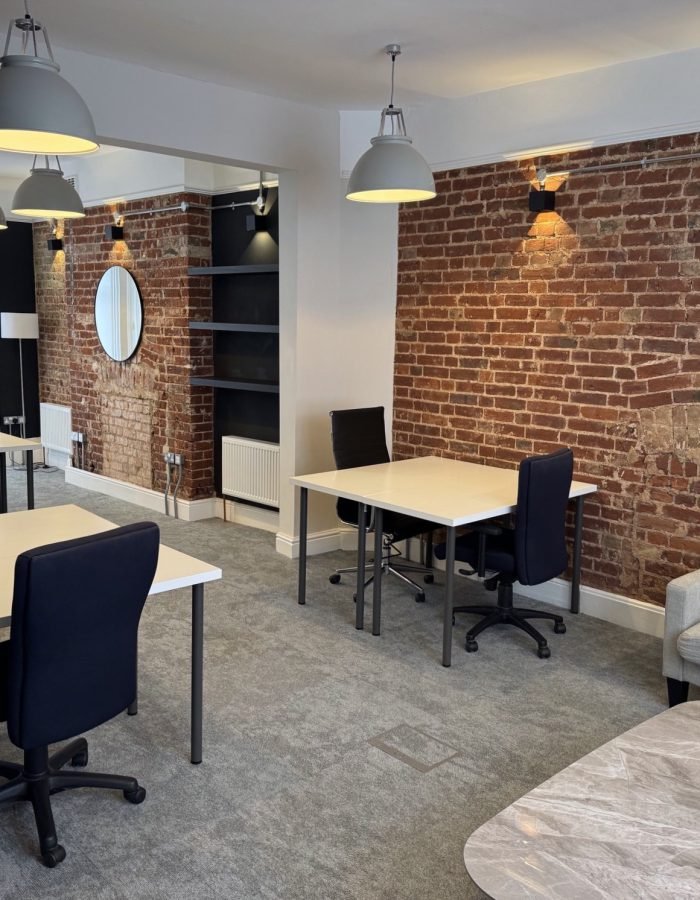 Modern renovated office space with exposed brick wall and pendant lighting