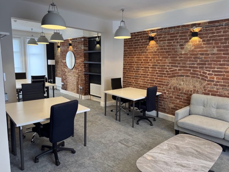 Modern renovated office space with exposed brick wall and pendant lighting